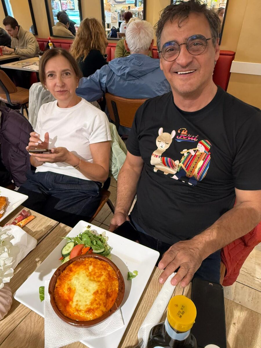 Two guests at their table, a dish of lasagne with salad in front of them
