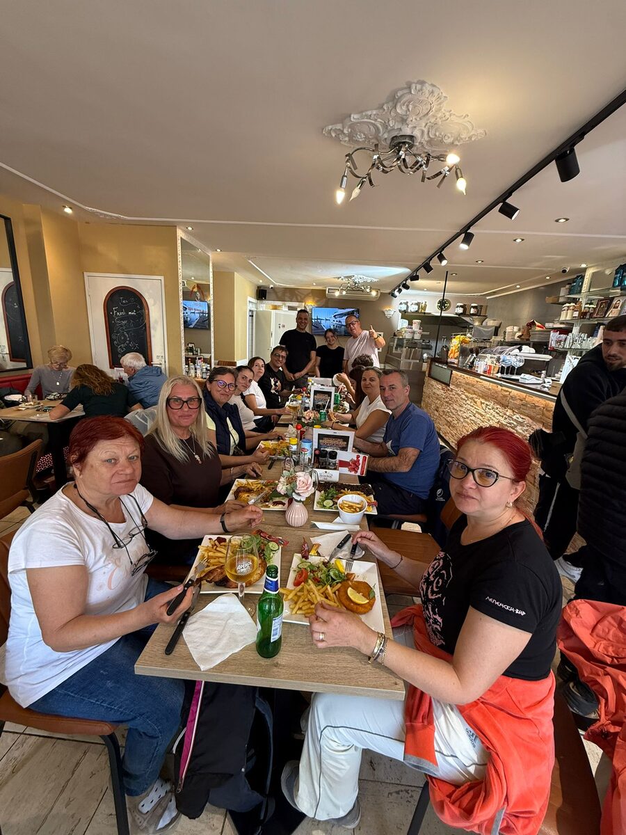 A big group at one long table inside Amarylles, plates of fries and salad in front of them and the counter behind